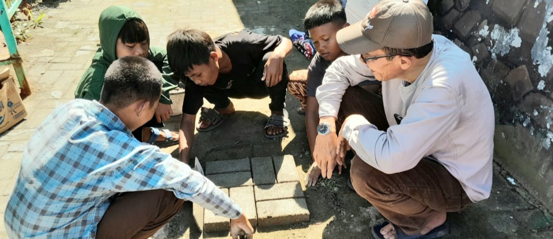 Ketua Tim PKM Unimed Prof Dr Ibnu Hajar MSi saat mengamati pembuatan batako dari pengelolaan limbah plastik untuk meningkatkan kreativitas anak- anak di Situs Kota Cina