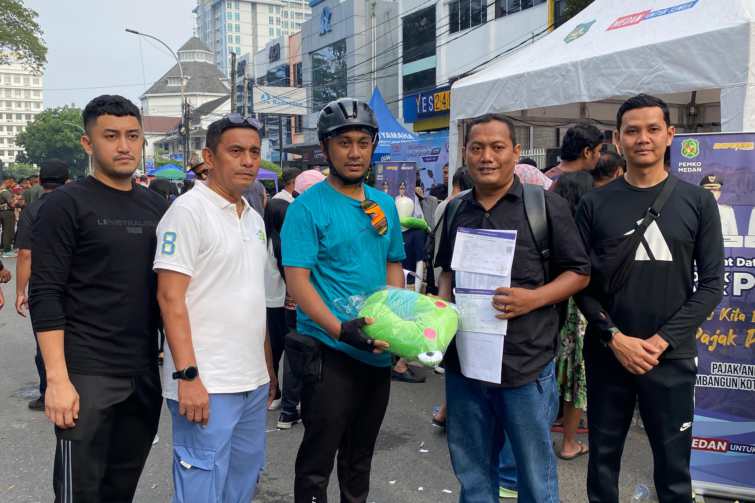 Plt. Kepala Bapenda Kota Medan, T. Roby Chairi didampingi Kabid. BPHTB & PBB, Sutan Partahi memberikan hadiah kepada warga masyarakat yang membayar PBB di Pojok PBB saat CFD Berlangsung