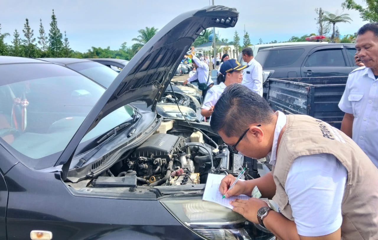 Seorang pegawai sedang melakukan pemeriksaan kendaraan dinas Pemkab Simalungun. Foto: IST